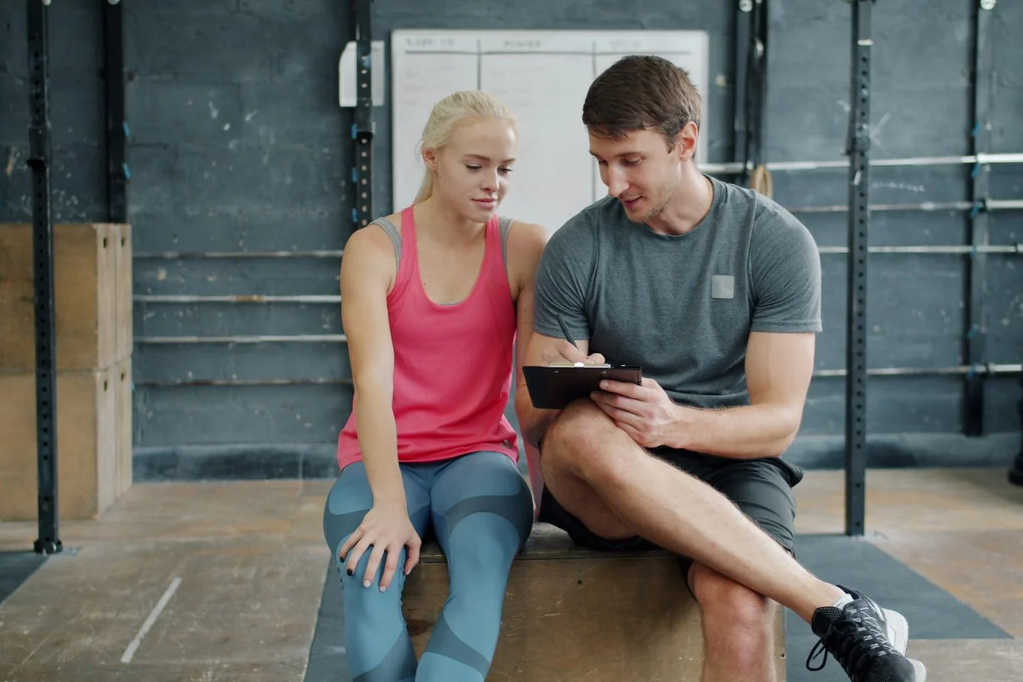 Two people reviewing training information on a tablet at a gym.