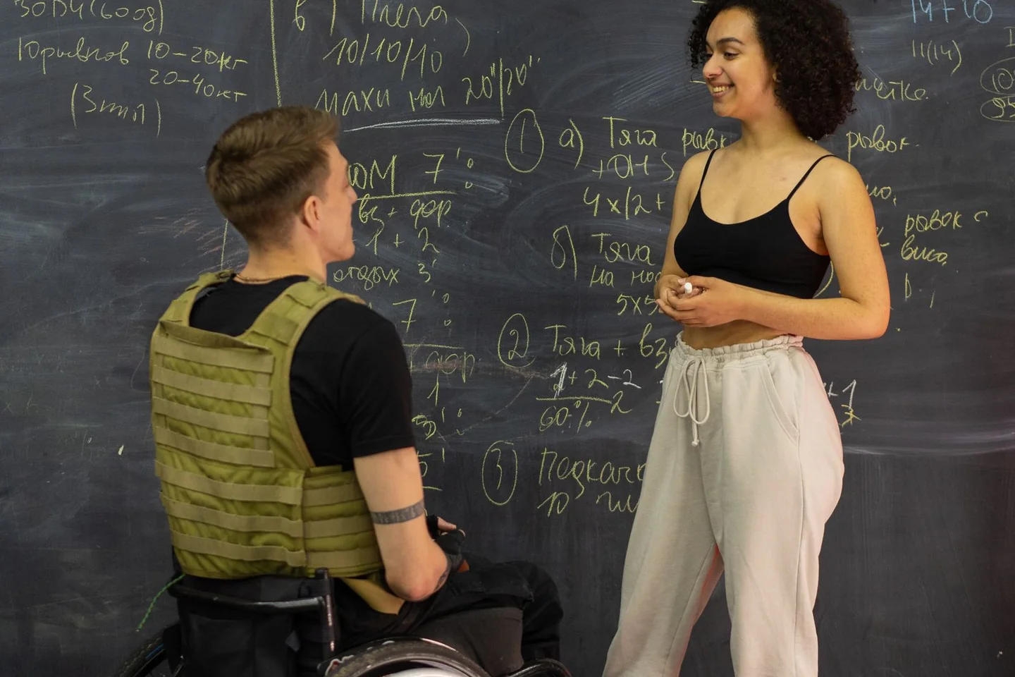 A trainer and gym user talking beside a whiteboard.