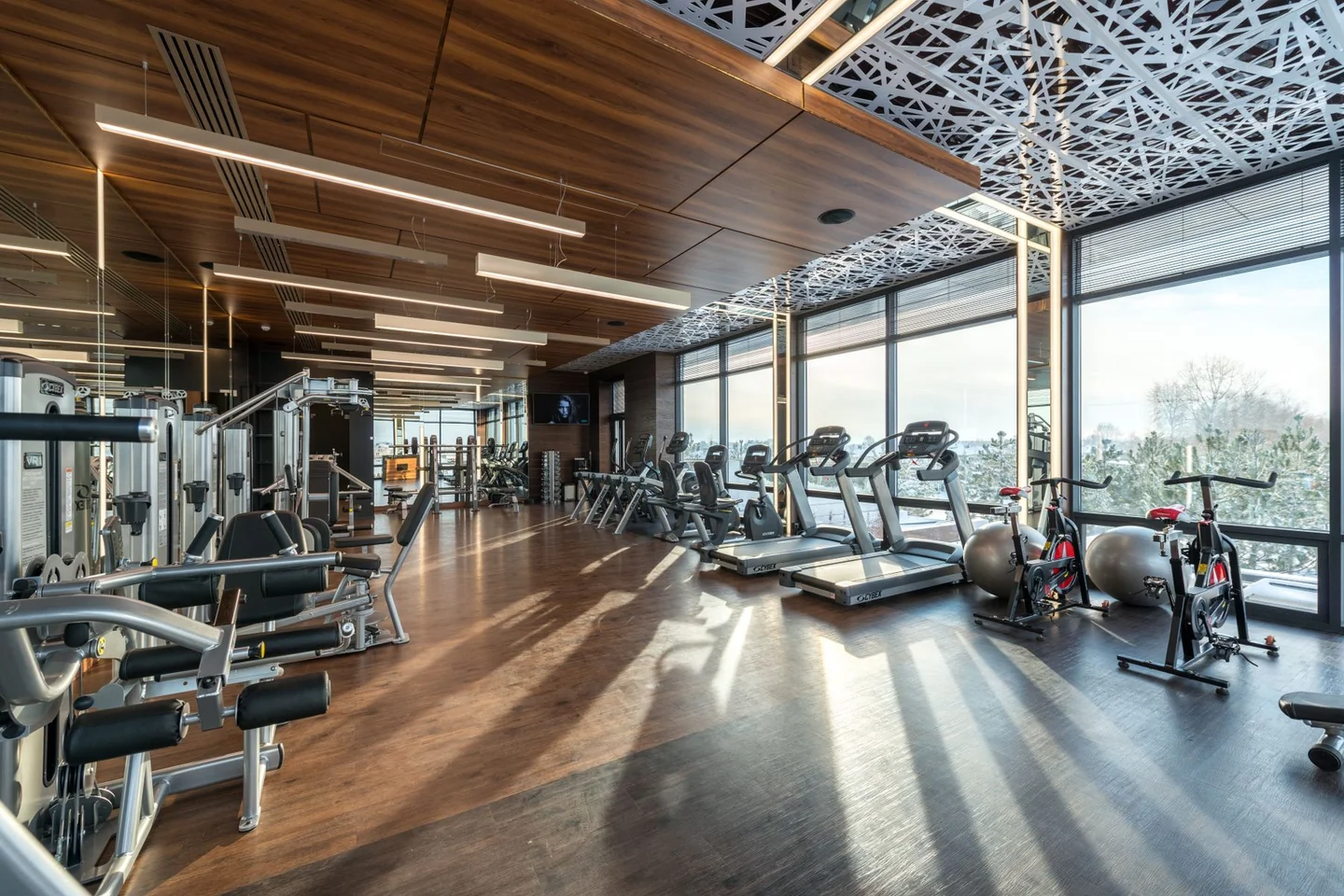 An open gym floor with resistance machines, treadmills and exercise bikes.