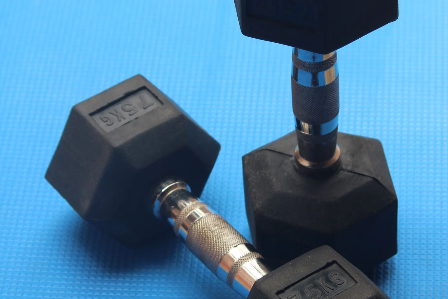A pair of dumbbells on a blue exercise mat.