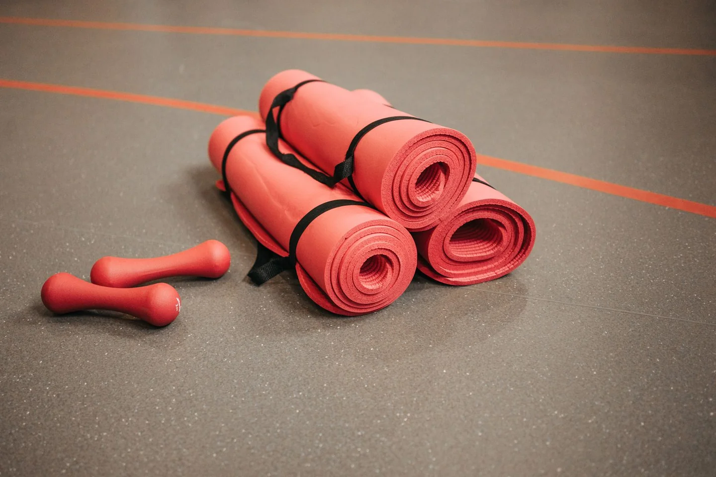 Rolled exercise mats beside small dumbbells.