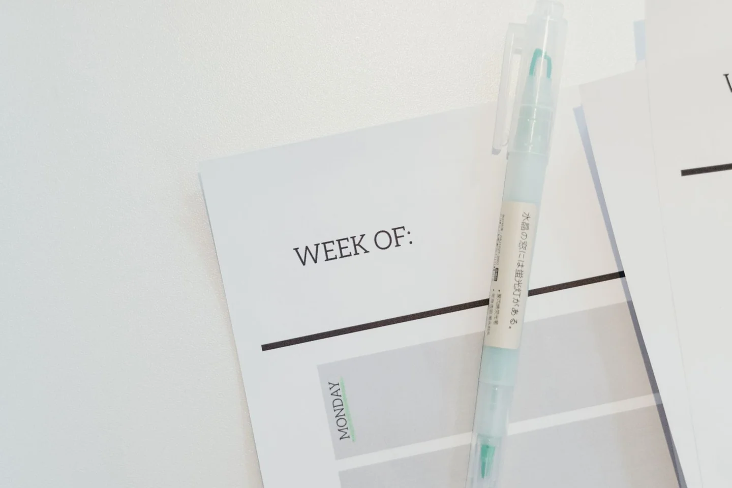 A weekly paper planner and pen on a desk.