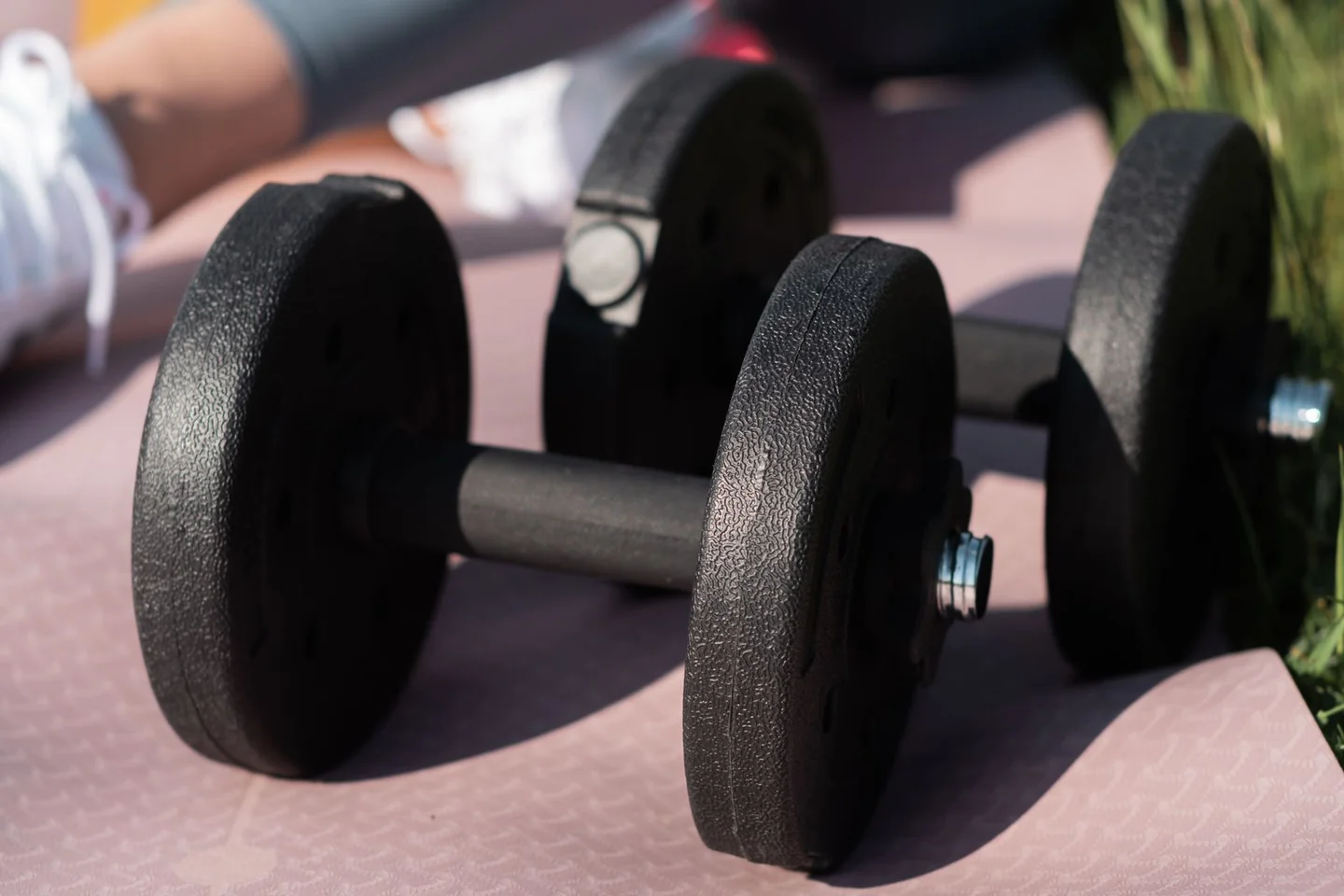 A pair of round dumbbells resting on an exercise mat.