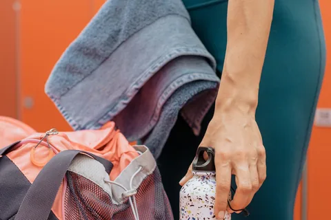A gym bag being packed with a towel and drinking bottle.