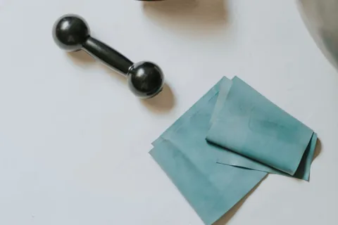 A folded flat resistance band beside a small dumbbell.