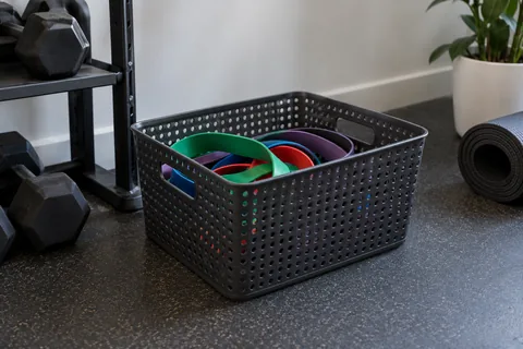 Loose resistance bands in a ventilated storage basket away from a window.