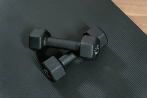 Two small hex dumbbells on a textured mat.