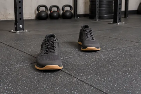 Two flat training shoes positioned in a staggered stance on rubber flooring.