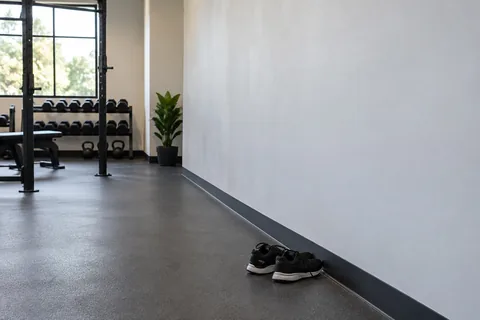 Clear solid gym wall with open floor space and training shoes.